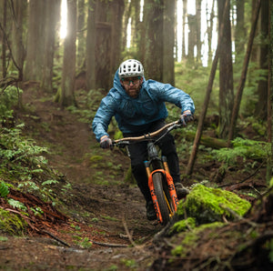 Image of Adapt Packable Mountain Bike Jacket - A versatile, ultra-lightweight, and packable cycling jacket made from 100% Rip-stop Nylon. Wind and rain resistant with Durable Water Repellent (DWR) treatment and fully taped seams to keep moisture out. Features an oversized hood for helmets, chest stash pocket, dual waist adjusters, and reflective logos for style and safety. Unisex fit, perfect for year-round mountain biking adventures.